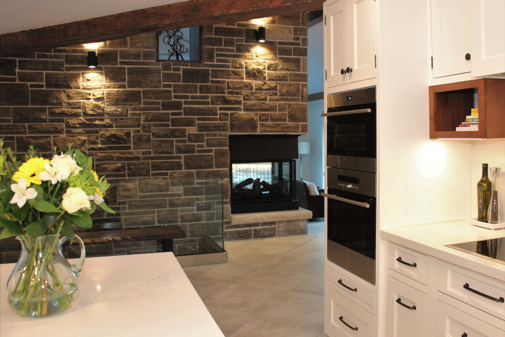 Photo of a large rustic galley kitchen/diner in Toronto with a submerged sink, recessed-panel cabinets, white cabinets, engineered stone countertops, white splashback, engineered quartz splashback, stainless steel appliances, porcelain flooring, an island, grey floors and white worktops.