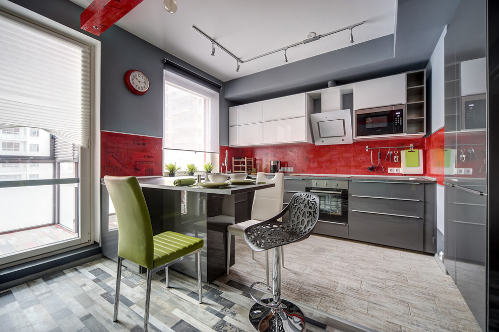 Пример оригинального дизайна: большая п-образная кухня в современном стиле с обеденным столом, двойной мойкой, плоскими фасадами, серыми фасадами, столешницей из ламината, красным фартуком, полом из керамической плитки и полуостровом