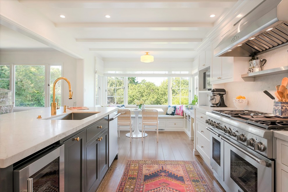 This is an example of a mid-sized transitional eat-in kitchen in San Francisco with an undermount sink, shaker cabinets, white cabinets, marble benchtops, white splashback, marble splashback, stainless steel appliances, medium hardwood floors, a peninsula and brown floor.
