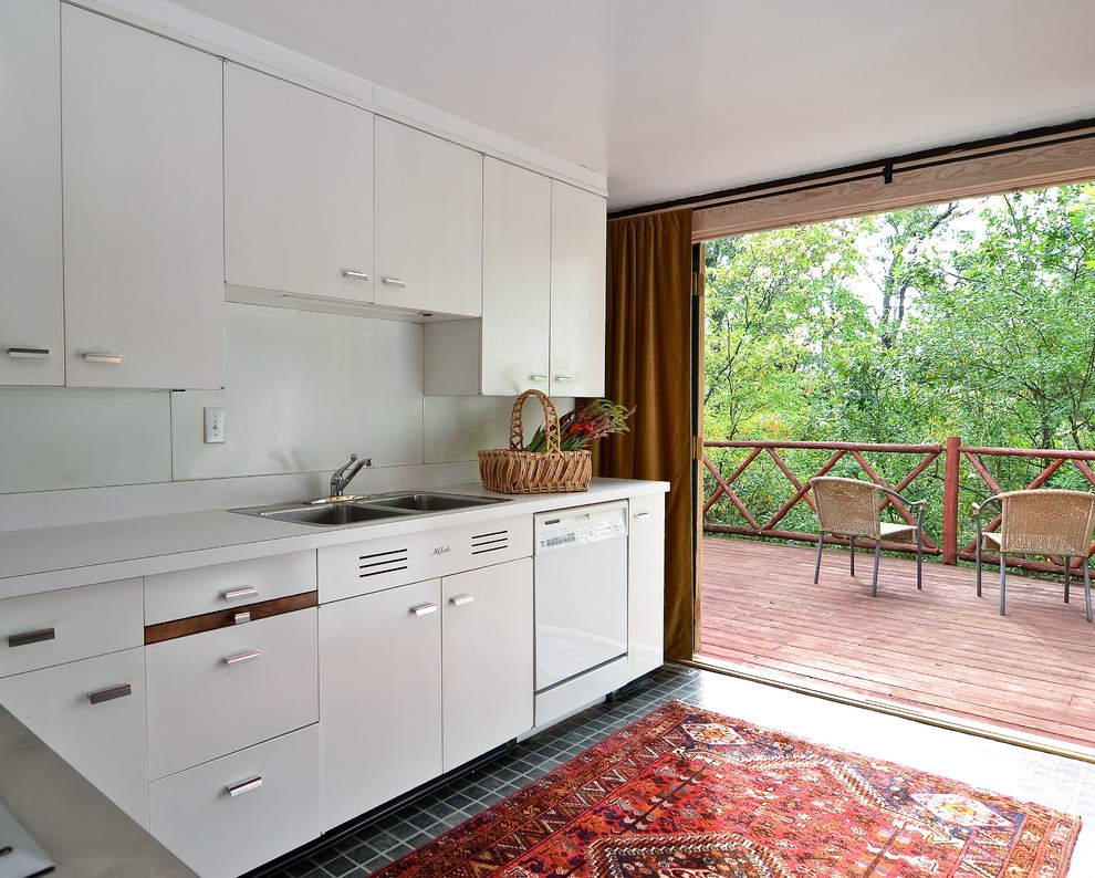 This is an example of a small contemporary kitchen in Chicago with a double-bowl sink, flat-panel cabinets, white cabinets, laminate benchtops, white splashback, white appliances, ceramic floors and no island.