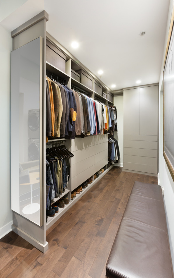 Design ideas for a small contemporary gender-neutral storage and wardrobe in Chicago with flat-panel cabinets, grey cabinets and medium hardwood floors.