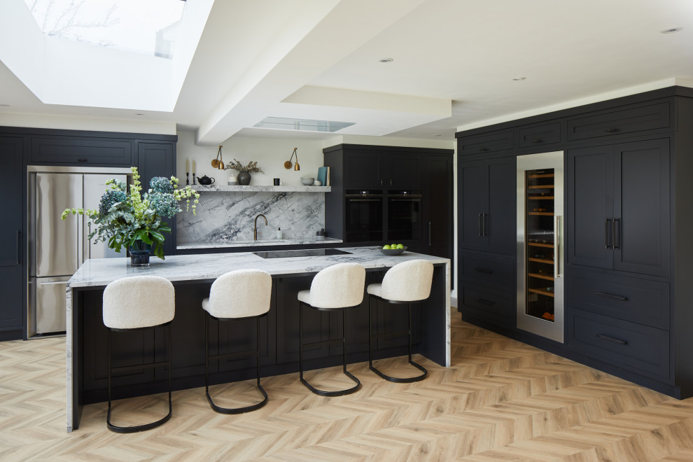 Large classic l-shaped kitchen/diner in London with recessed-panel cabinets, black cabinets and an island.