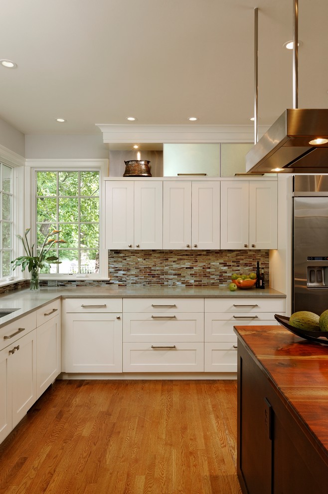 Enclosed kitchen - mid-sized transitional u-shaped medium tone wood floor and brown floor enclosed kitchen idea in DC Metro with an undermount sink, shaker cabinets, white cabinets, brown backsplash, glass tile backsplash, stainless steel appliances and an island