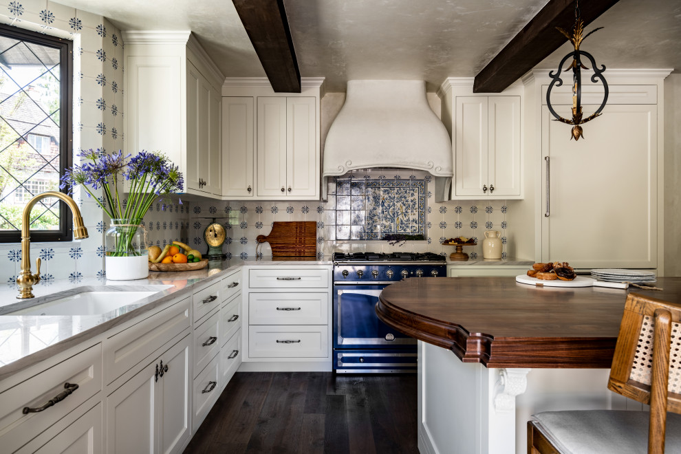 Klassisk inredning av ett stort vit vitt kök, med en enkel diskho, luckor med infälld panel, vita skåp, marmorbänkskiva, flerfärgad stänkskydd, stänkskydd i porslinskakel, färgglada vitvaror, mörkt trägolv, en köksö och brunt golv