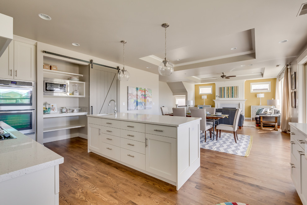 Example of a large transitional light wood floor eat-in kitchen design in Boise with shaker cabinets, white cabinets, quartzite countertops, stainless steel appliances and an island