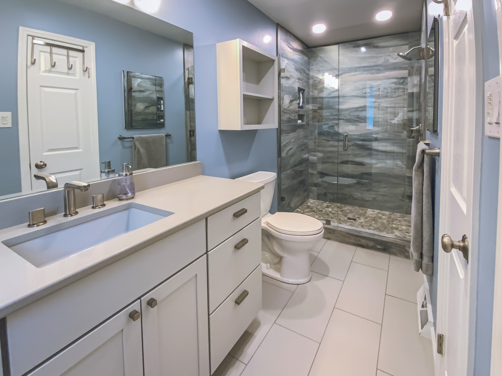 Photo of a mid-sized contemporary master bathroom in Other with shaker cabinets, grey cabinets, an alcove shower, a one-piece toilet, blue walls, porcelain floors, an integrated sink, grey floor, a hinged shower door, grey benchtops, a niche, a single vanity and a built-in vanity.