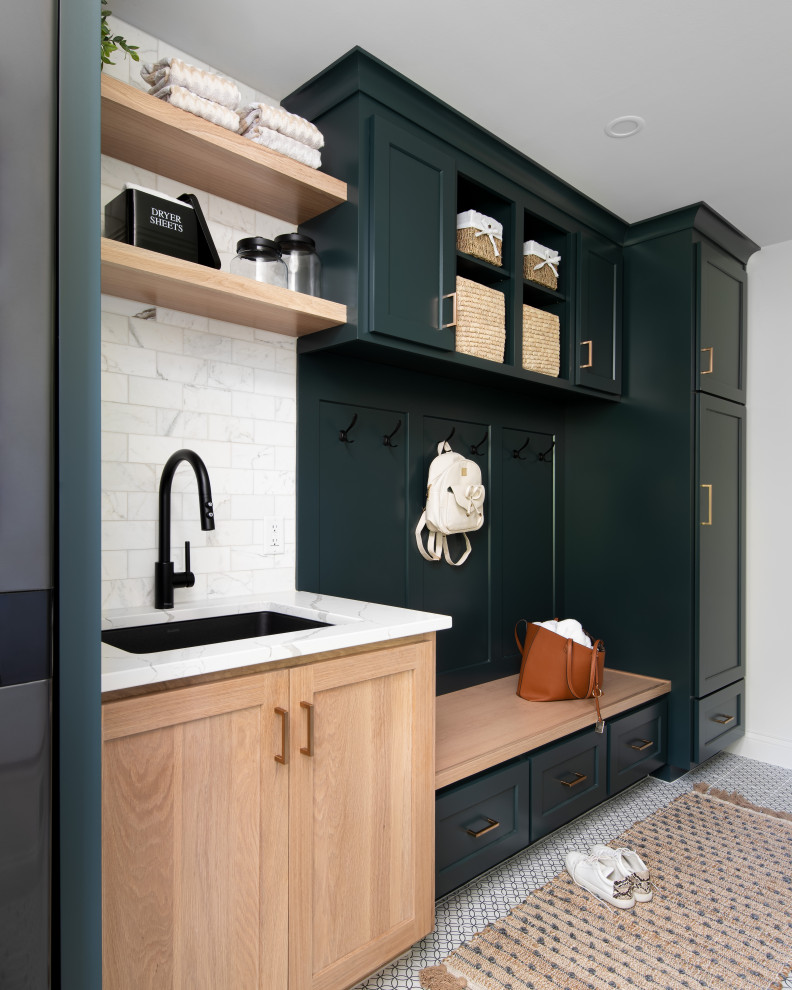 Inspiration for a mid-sized transitional single-wall dedicated laundry room in Kansas City with an undermount sink, recessed-panel cabinets, green cabinets, quartz benchtops, white splashback, marble splashback, white walls, porcelain floors, a stacked washer and dryer, white floor and white benchtop.