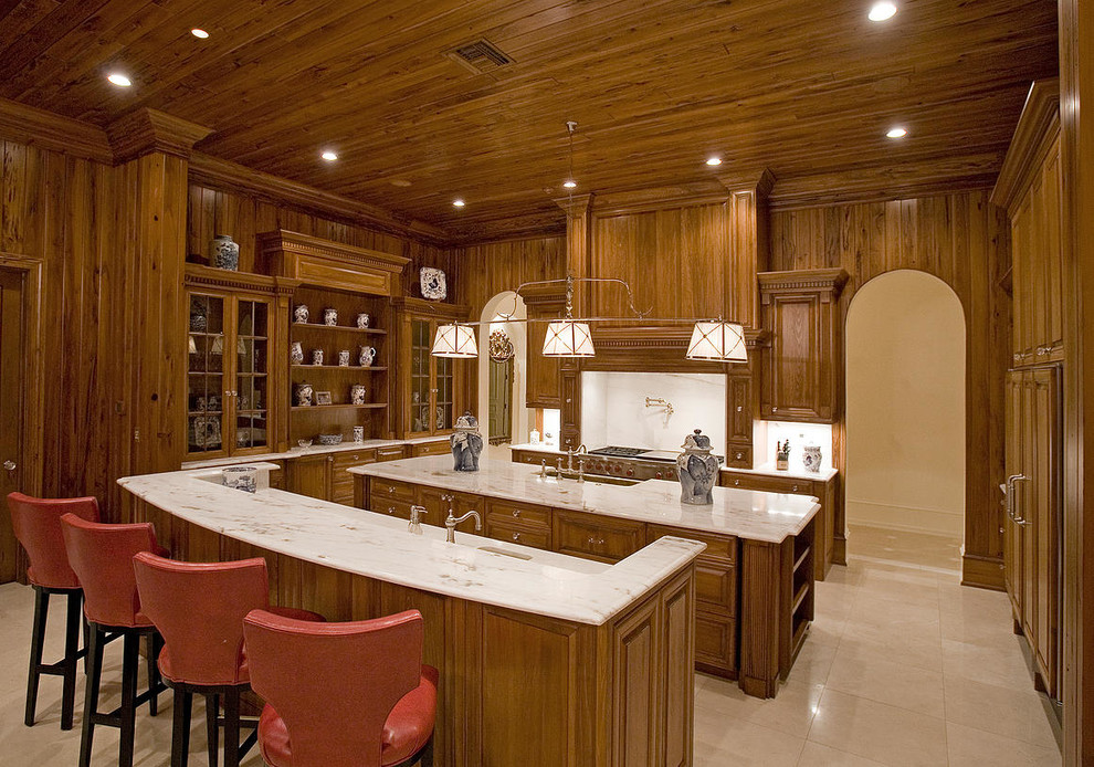Large country u-shaped eat-in kitchen in New York with a farmhouse sink, raised-panel cabinets, medium wood cabinets, marble benchtops, ceramic splashback, stainless steel appliances, ceramic floors and multiple islands.