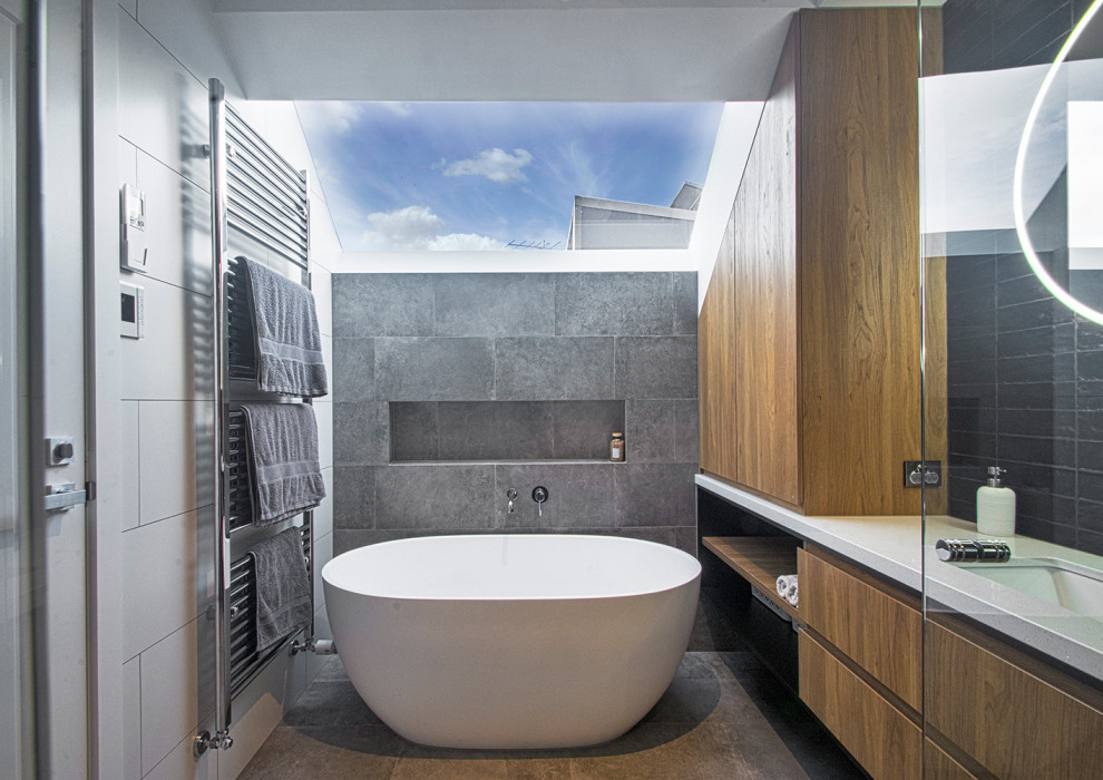 Стильный дизайн: маленькая детская ванная комната в стиле модернизм с фасадами островного типа, белыми фасадами, отдельно стоящей ванной, открытым душем, унитазом-моноблоком, серой плиткой, керамической плиткой, белыми стенами, полом из керамической плитки, врезной раковиной, столешницей из искусственного кварца, серым полом, душем с распашными дверями, белой столешницей, тумбой под одну раковину и подвесной тумбой для на участке и в саду - последний тренд
