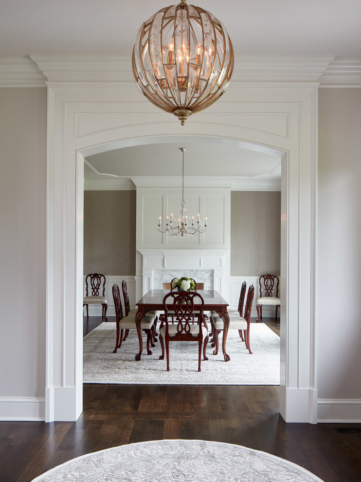 Traditional dining room in Chicago with dark hardwood floors, grey walls and a standard fireplace.