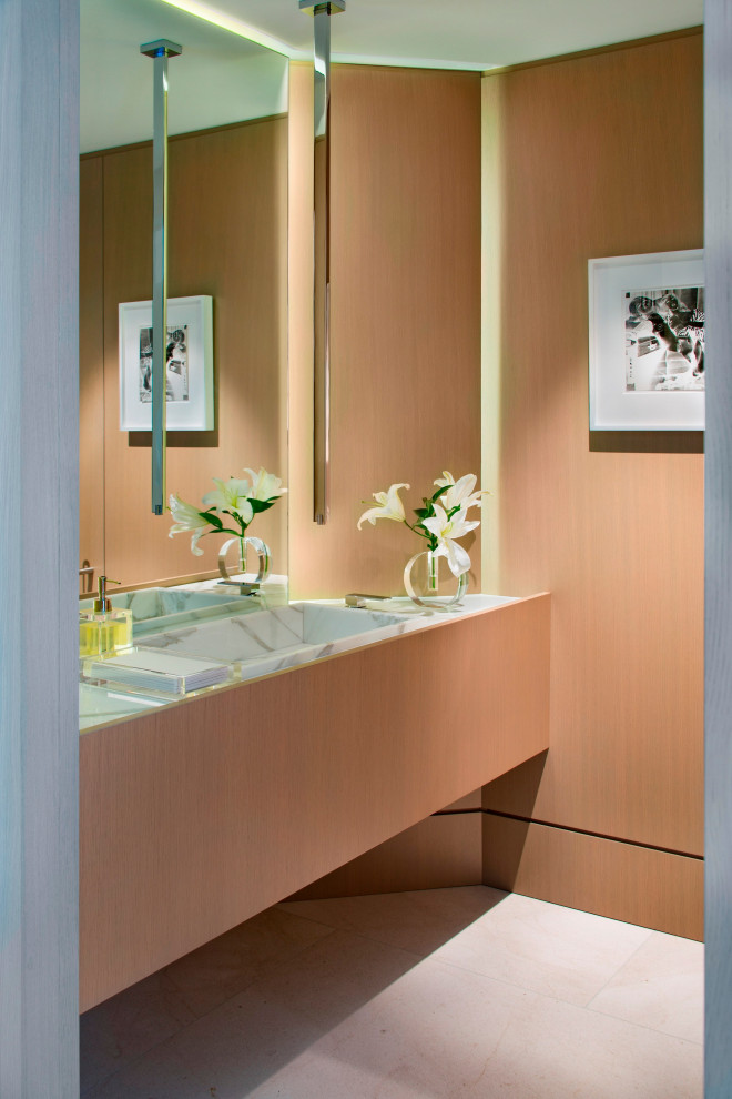 Immagine di un piccolo bagno di servizio eclettico con ante in legno scuro, pareti beige, pavimento in pietra calcarea, lavabo integrato, top in marmo, mobile bagno sospeso e pannellatura