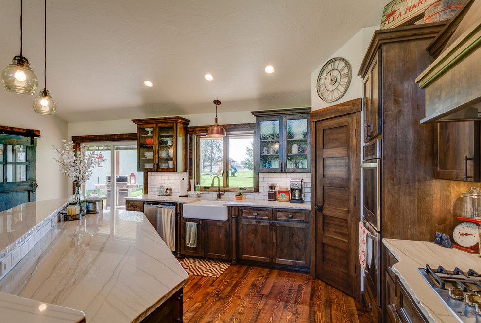 Example of a mid-sized mountain style u-shaped medium tone wood floor kitchen pantry design in Seattle with an undermount sink, shaker cabinets, medium tone wood cabinets, quartzite countertops, white backsplash, subway tile backsplash, stainless steel appliances and an island