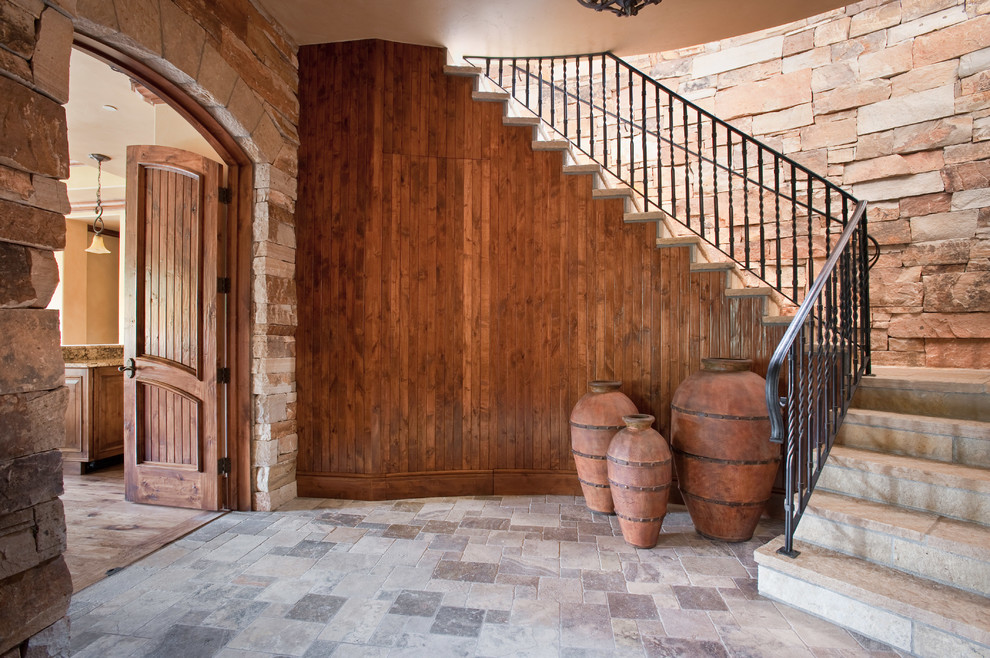 Example of a huge mountain style limestone floor foyer design in Denver with brown walls and a dark wood front door