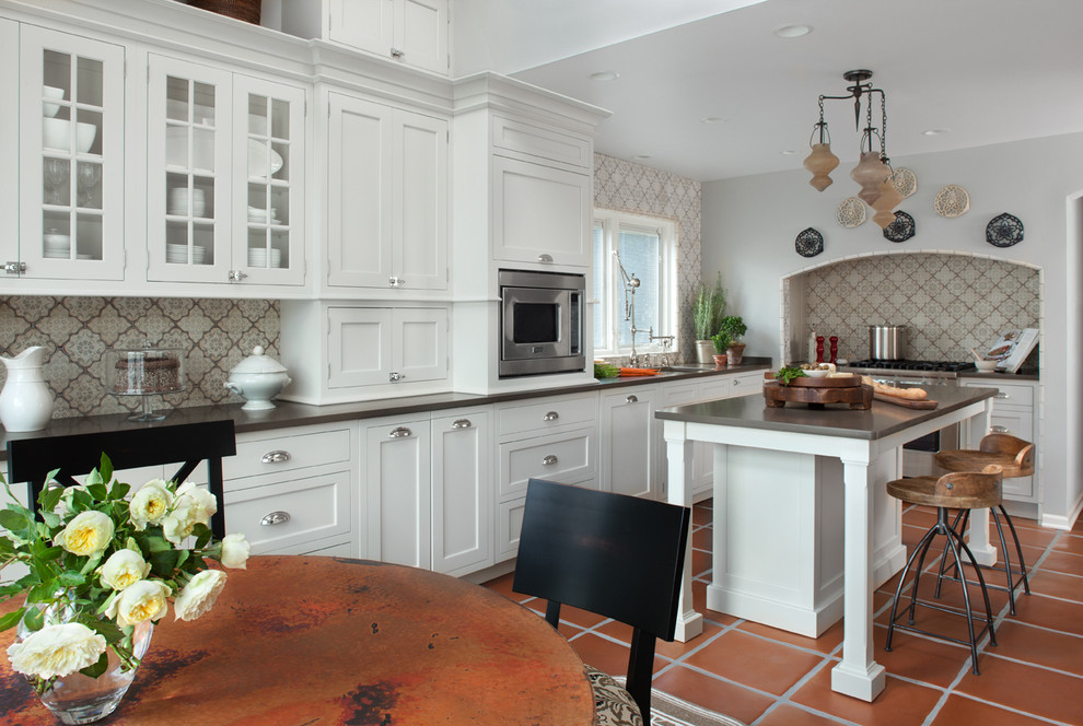 This is an example of a traditional l-shaped eat-in kitchen in Detroit with an undermount sink, shaker cabinets, white cabinets, multi-coloured splashback and stainless steel appliances.