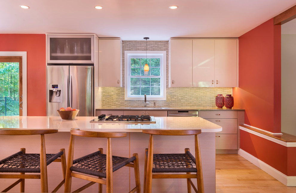 This is an example of a large contemporary u-shaped eat-in kitchen in Boston with flat-panel cabinets, white cabinets, quartz benchtops, multi-coloured splashback, stainless steel appliances, light hardwood floors and with island.