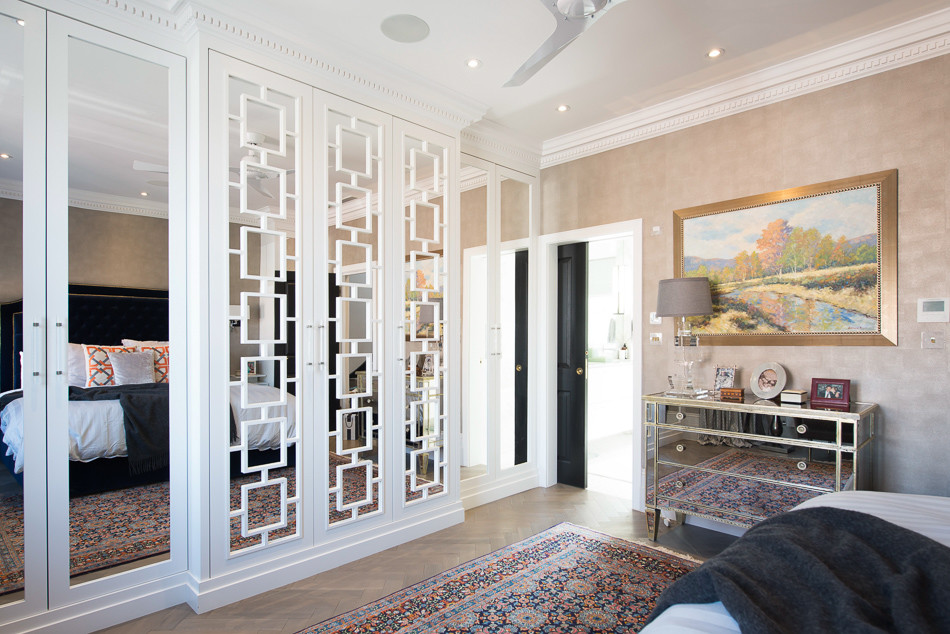This is an example of a large contemporary gender-neutral built-in wardrobe in London with shaker cabinets, white cabinets, medium hardwood floors and brown floor.