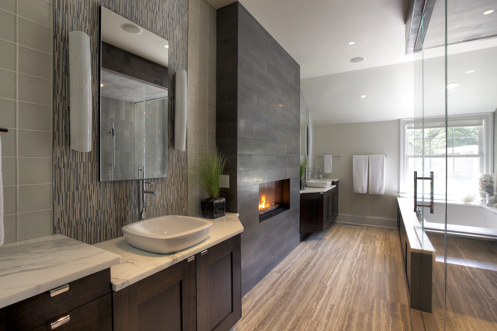 Large contemporary bathroom in New York with marble benchtops, a vessel sink, an undermount tub, gray tile, glass tile, grey walls and travertine floors.