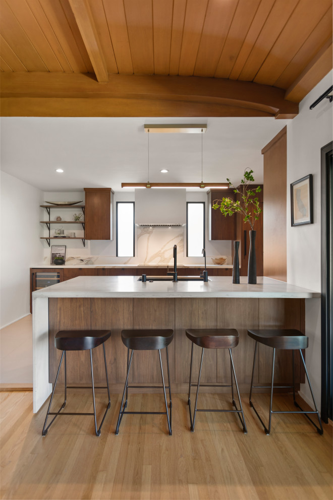 Photo of a mid-sized contemporary galley kitchen in Los Angeles with an undermount sink, flat-panel cabinets, medium wood cabinets, concrete benchtops, engineered quartz splashback, panelled appliances, porcelain floors, with island, grey floor, grey benchtop and wood.