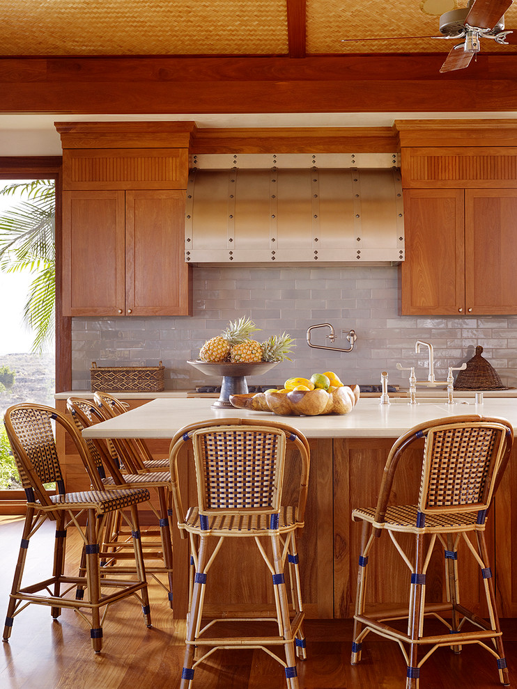 This is an example of a large tropical l-shaped eat-in kitchen in Hawaii with medium wood cabinets, grey splashback, subway tile splashback, an undermount sink, recessed-panel cabinets, marble benchtops, medium hardwood floors and with island.