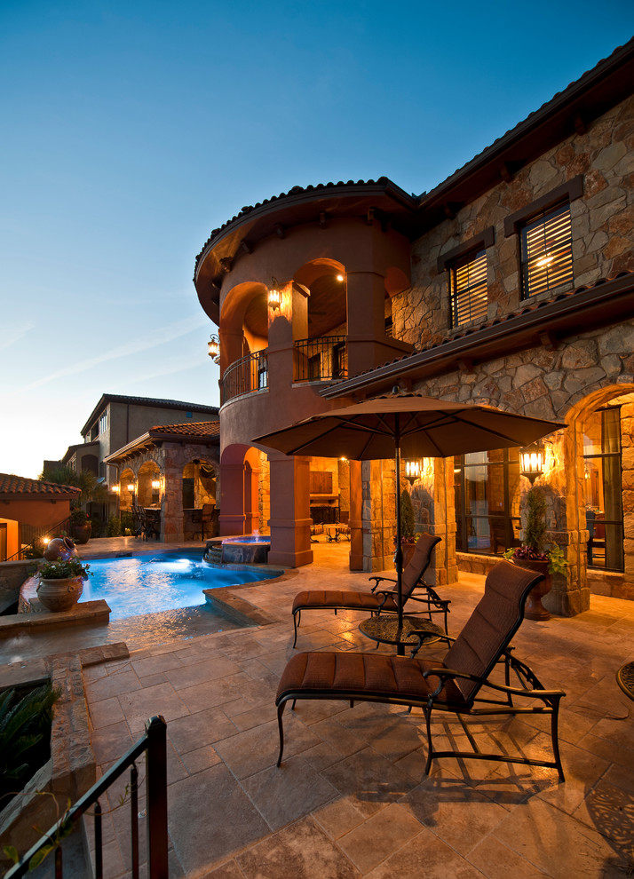 Large mediterranean backyard patio in Austin with natural stone pavers and a roof extension.