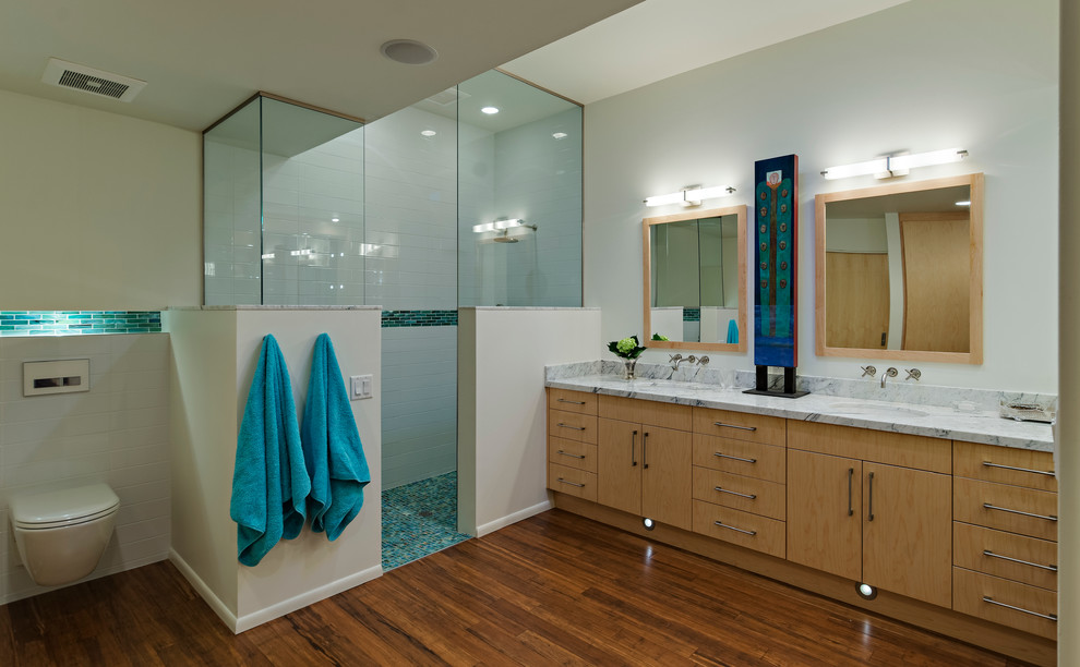 Inspiration for a large modern master bathroom in Phoenix with an undermount sink, flat-panel cabinets, light wood cabinets, marble benchtops, a wall-mount toilet, glass tile, an alcove shower, beige walls, dark hardwood floors, brown floor, an open shower and grey benchtops.