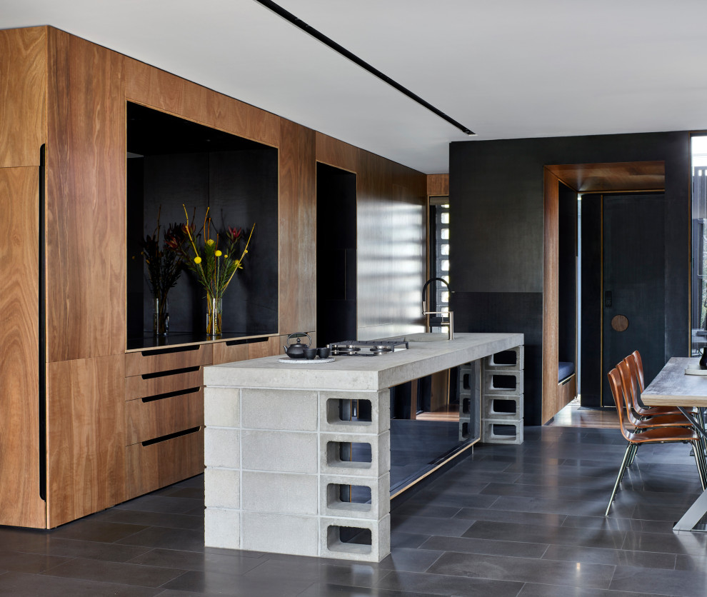 Mid-sized contemporary galley open plan kitchen in Melbourne with an undermount sink, recessed-panel cabinets, brown cabinets, concrete benchtops, white splashback, mirror splashback, panelled appliances, with island, grey floor, grey benchtop and recessed.