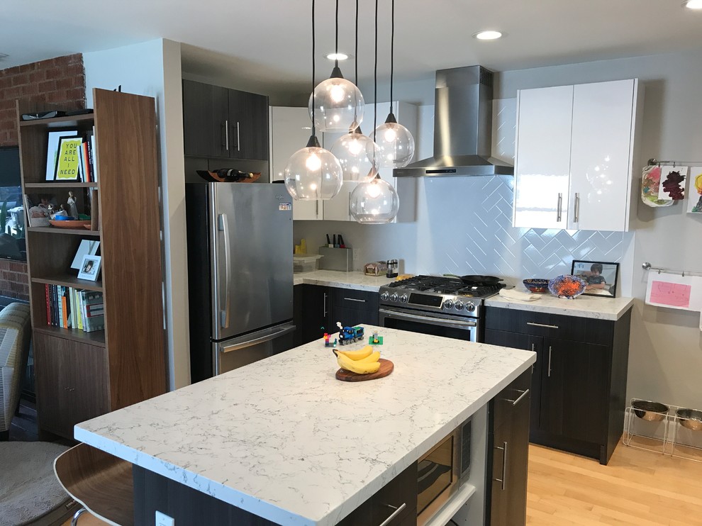 This is an example of a large contemporary l-shaped open plan kitchen in Los Angeles with a farmhouse sink, flat-panel cabinets, dark wood cabinets, quartzite benchtops, subway tile splashback, stainless steel appliances, light hardwood floors, with island, yellow floor, white splashback and white benchtop.