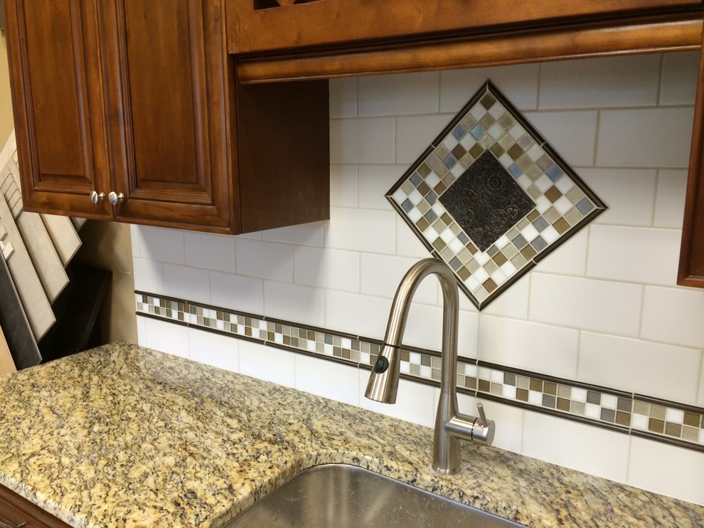 Example of a transitional single-wall porcelain tile enclosed kitchen design with a drop-in sink, raised-panel cabinets, medium tone wood cabinets, granite countertops, white backsplash, porcelain backsplash, stainless steel appliances and no island