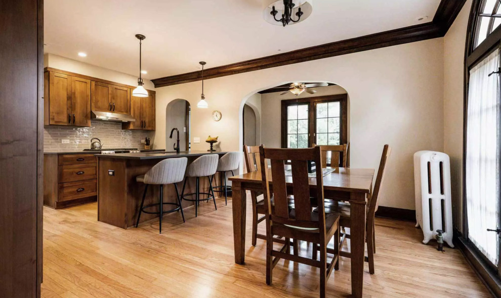 Example of a small mountain style galley medium tone wood floor and brown floor eat-in kitchen design with a drop-in sink, flat-panel cabinets, dark wood cabinets, gray backsplash, glass tile backsplash, stainless steel appliances, an island and gray countertops