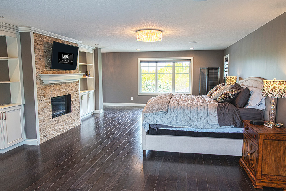 Inspiration for a large arts and crafts master bedroom in Other with grey walls, dark hardwood floors, a ribbon fireplace, a stone fireplace surround and brown floor.