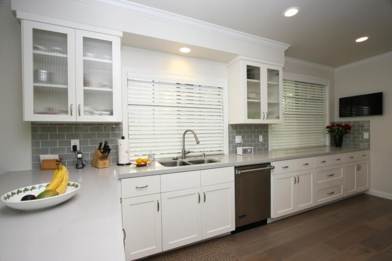 Inspiration for a large transitional l-shaped medium tone wood floor and brown floor eat-in kitchen remodel in Los Angeles with an undermount sink, shaker cabinets, white cabinets, soapstone countertops, metallic backsplash, subway tile backsplash, stainless steel appliances and a peninsula