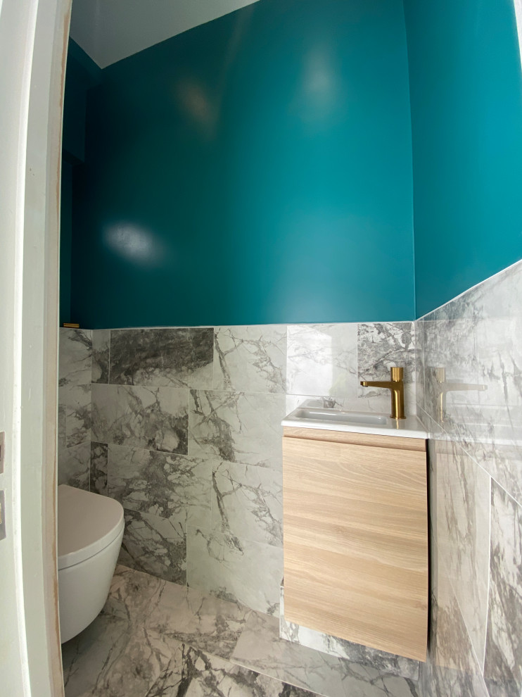 Kleine Moderne Gästetoilette mit flächenbündigen Schrankfronten, hellen Holzschränken, Wandtoilette, farbigen Fliesen und schwebendem Waschtisch in London