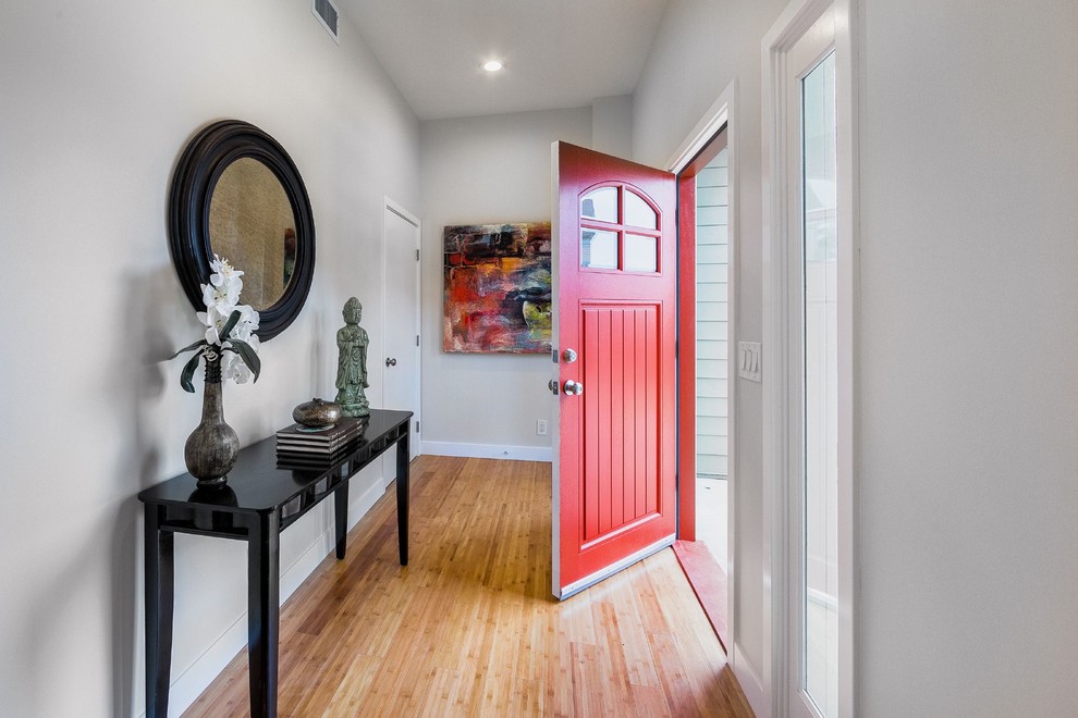 Inspiration for a contemporary front door in Los Angeles with white walls, bamboo floors, a single front door and a red front door.