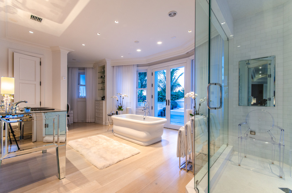 Photo of an expansive tropical master bathroom in Miami with an undermount sink, a freestanding tub, a corner shower, white tile, subway tile, white walls and light hardwood floors.