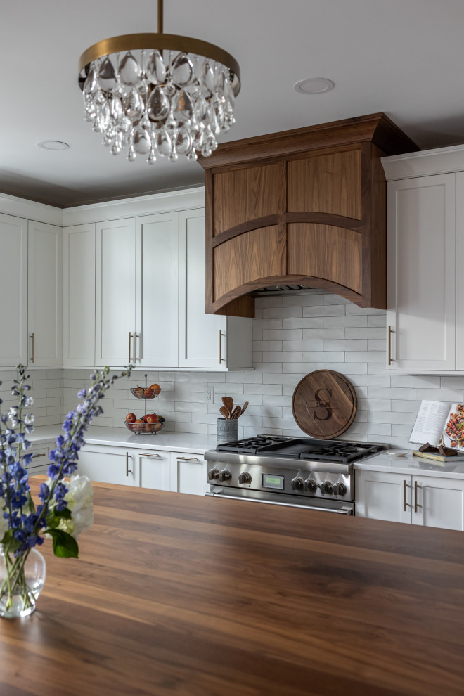 Example of a large classic medium tone wood floor open concept kitchen design in Philadelphia with an undermount sink, recessed-panel cabinets, wood countertops, white backsplash, porcelain backsplash, stainless steel appliances and an island