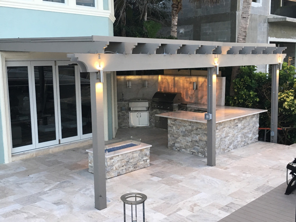 Inspiration for a large contemporary backyard patio in Miami with an outdoor kitchen, natural stone pavers and a pergola.