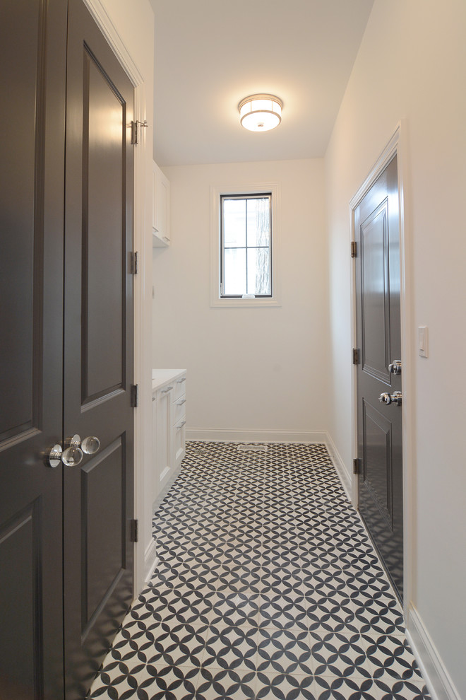 This is an example of a small transitional single-wall dedicated laundry room in Chicago with a drop-in sink, recessed-panel cabinets, white cabinets, quartzite benchtops, white walls, concrete floors and a stacked washer and dryer.