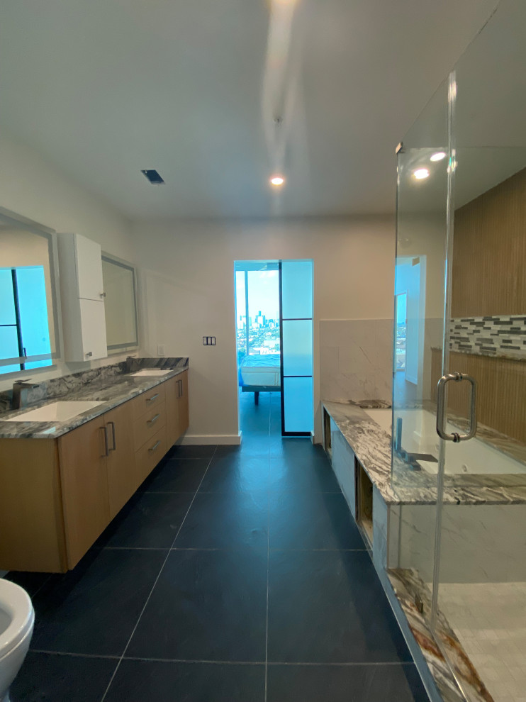 This is an example of a large eclectic master bathroom in Houston with raised-panel cabinets, white cabinets, a hot tub, a shower/bathtub combo, a bidet, white tile, mosaic tile, white walls, ceramic floors, a wall-mount sink, marble benchtops, black floor, an open shower, multi-coloured benchtops, an enclosed toilet, a double vanity, a floating vanity and vaulted.