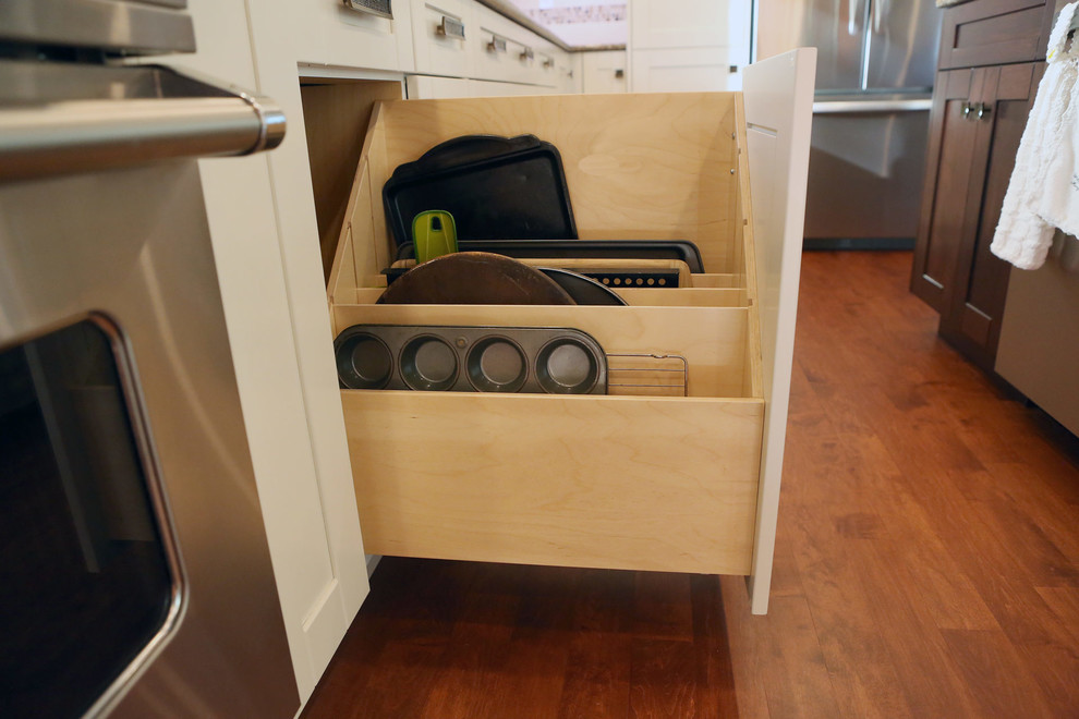 Example of a mid-sized transitional l-shaped medium tone wood floor and brown floor open concept kitchen design in Calgary with an undermount sink, shaker cabinets, white cabinets, granite countertops, white backsplash, mosaic tile backsplash, stainless steel appliances, an island and beige countertops