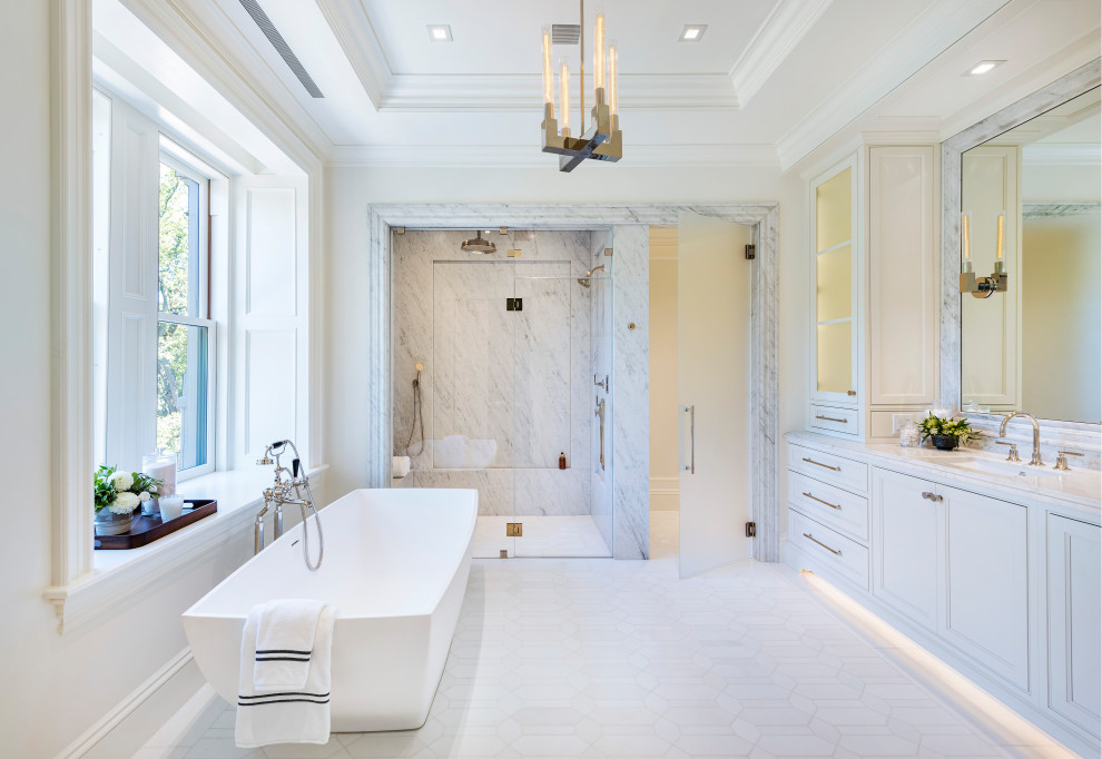 Design ideas for a transitional master bathroom in Boston with recessed-panel cabinets, white cabinets, a freestanding tub, a curbless shower, a bidet, gray tile, marble, white walls, mosaic tile floors, an undermount sink, marble benchtops, white floor, a hinged shower door, grey benchtops, an enclosed toilet, a double vanity, a built-in vanity and recessed.