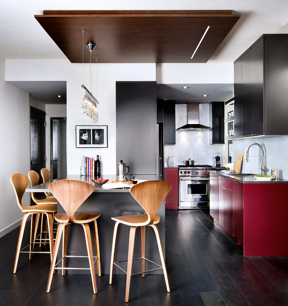 This is an example of a modern u-shaped kitchen in Toronto with flat-panel cabinets, red cabinets, mosaic tile splashback and stainless steel appliances.
