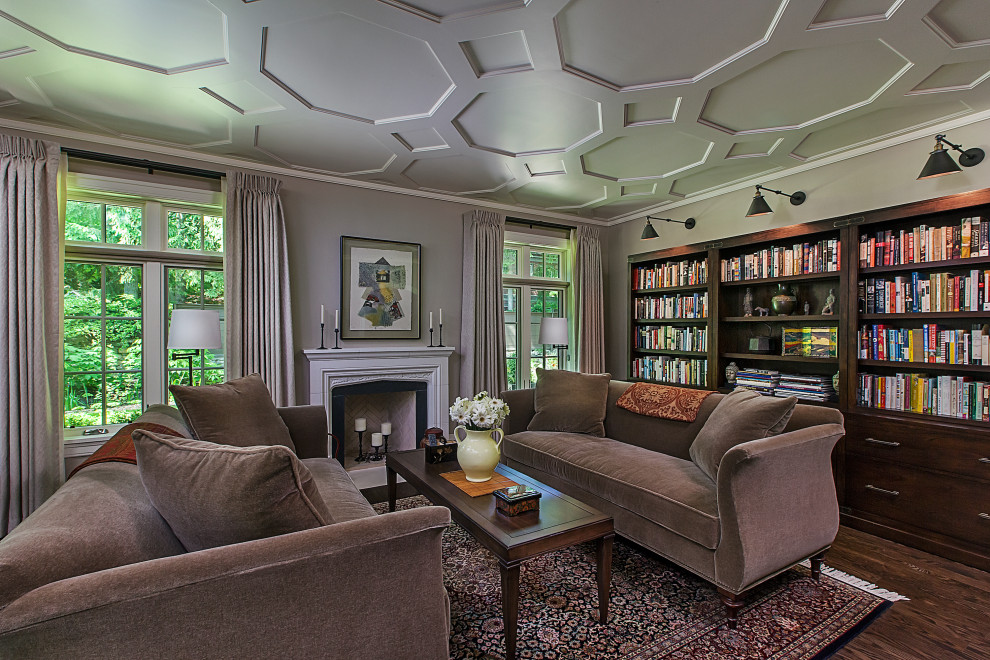 Mid-sized traditional enclosed living room in Detroit with a library, beige walls, dark hardwood floors, a standard fireplace, a stone fireplace surround, a freestanding tv, brown floor and coffered.