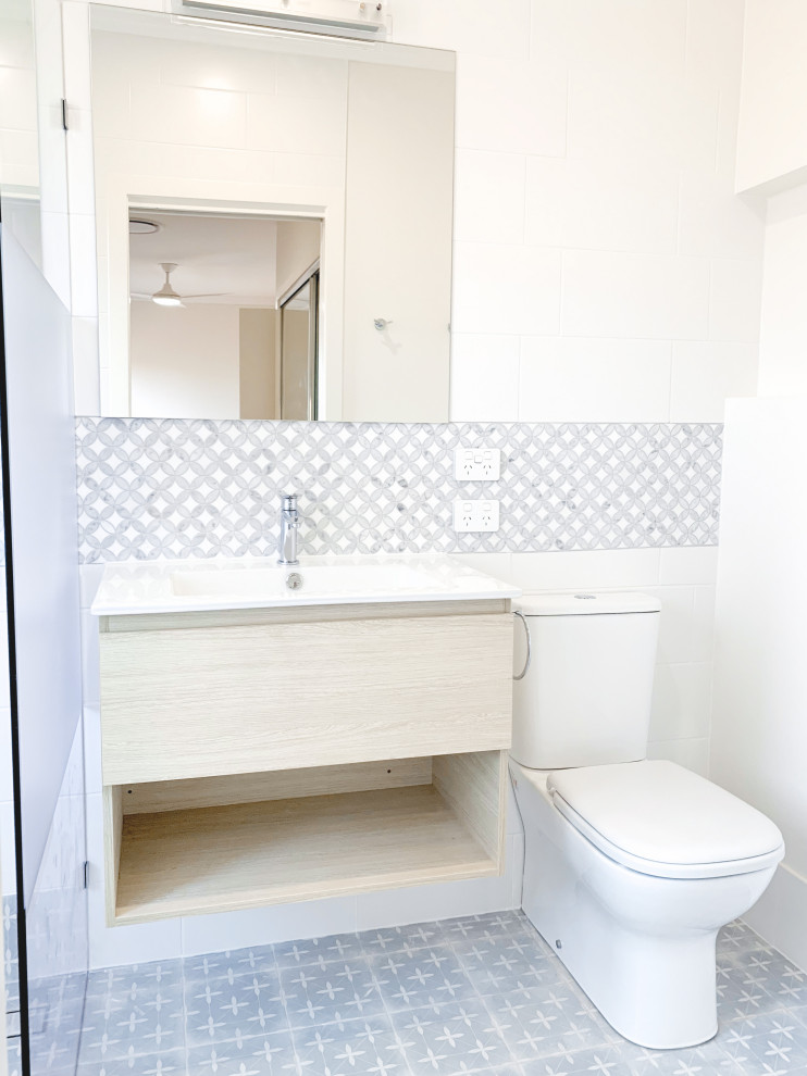 Photo of a small 3/4 wet room bathroom in Brisbane with a wall-mount toilet, multi-coloured tile, ceramic tile, ceramic floors, an integrated sink, multi-coloured floor, an open shower, a niche, a floating vanity and decorative wall panelling.
