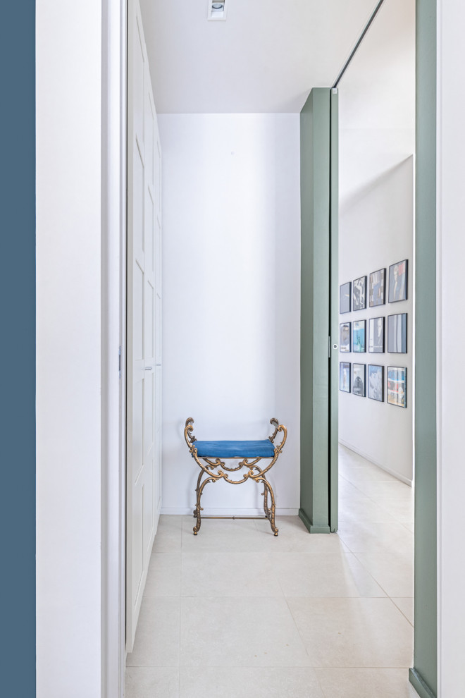 This is an example of a mid-sized contemporary gender-neutral built-in wardrobe in Turin with recessed-panel cabinets, white cabinets, porcelain floors, beige floor and recessed.
