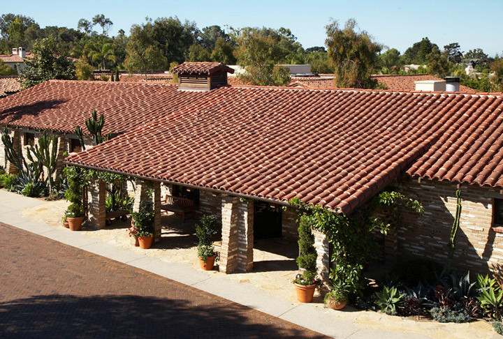 Mid-sized mediterranean one-storey beige house exterior in San Diego with stone veneer, a gable roof and a tile roof.