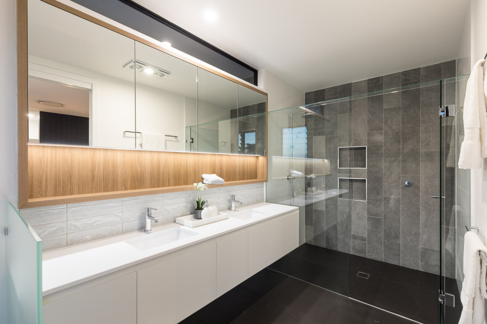 Photo of a contemporary master bathroom in Brisbane with flat-panel cabinets, white cabinets, a curbless shower, white walls, an undermount sink, black floor, a hinged shower door and white benchtops.
