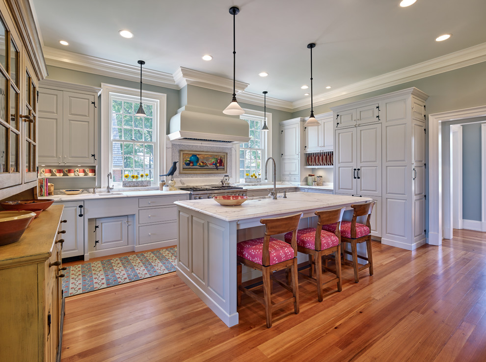 Photo of a traditional l-shaped kitchen in Baltimore with raised-panel cabinets, grey cabinets, panelled appliances, medium hardwood floors, with island and brown floor.