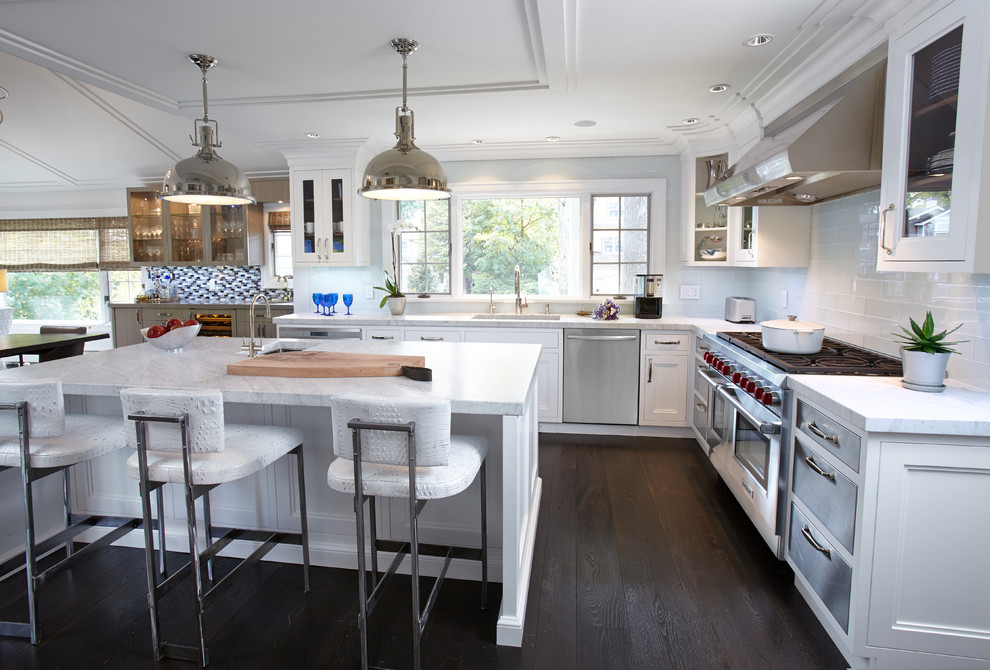 Eat-in kitchen - large transitional l-shaped dark wood floor eat-in kitchen idea in New York with an undermount sink, glass-front cabinets, white cabinets, marble countertops, white backsplash, glass tile backsplash, stainless steel appliances and an island