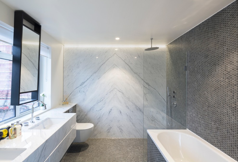 Inspiration for a contemporary master bathroom in London with flat-panel cabinets, white cabinets, marble benchtops, white tile, a drop-in tub, a curbless shower, a one-piece toilet, an undermount sink, grey walls, mosaic tile floors and marble.