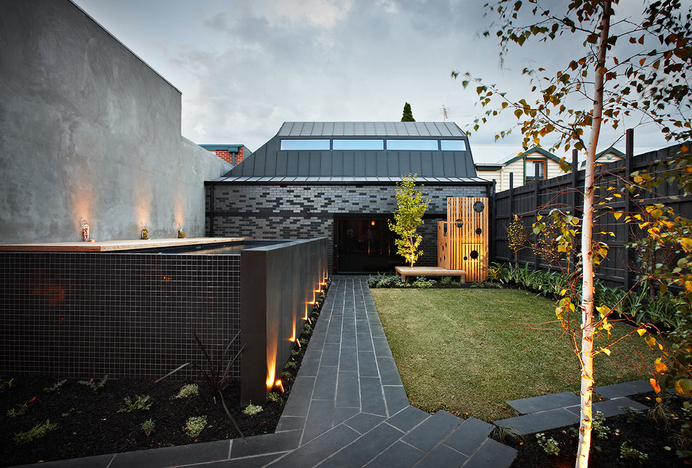 Contemporary backyard garden in Melbourne with natural stone pavers.